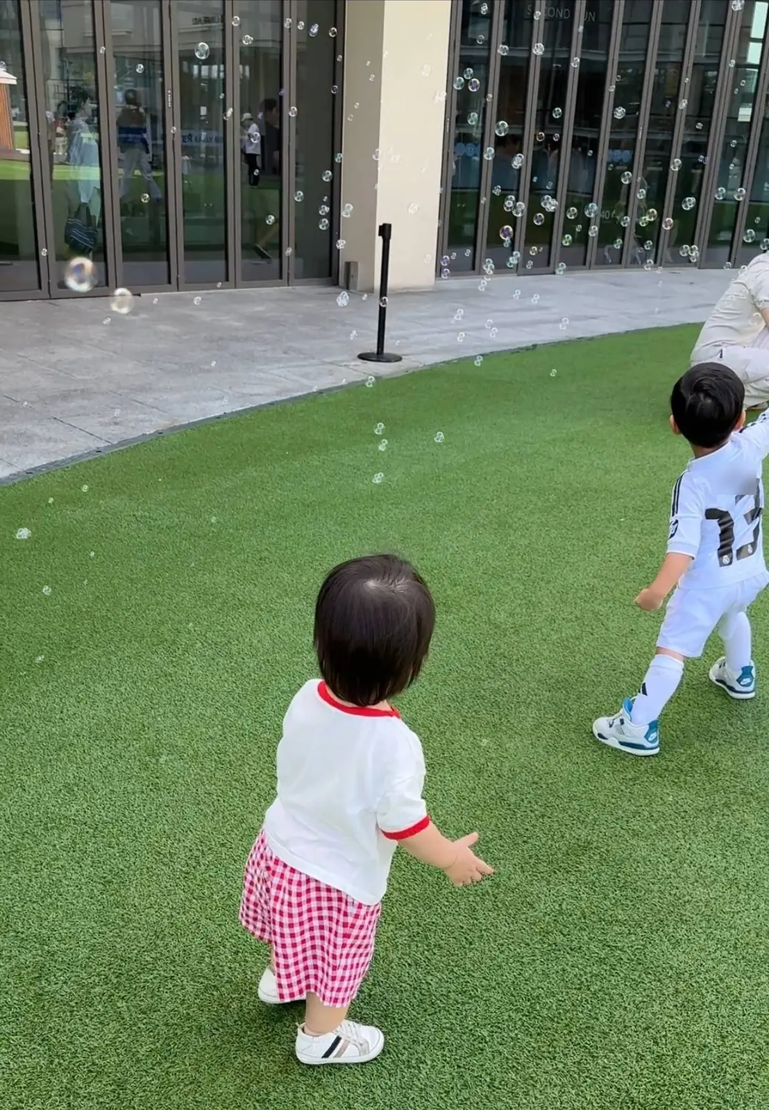 롯데프리미엄아울렛 의왕점 타임빌라스 잔디밭에서 비눗방울을 잡으려는 아이