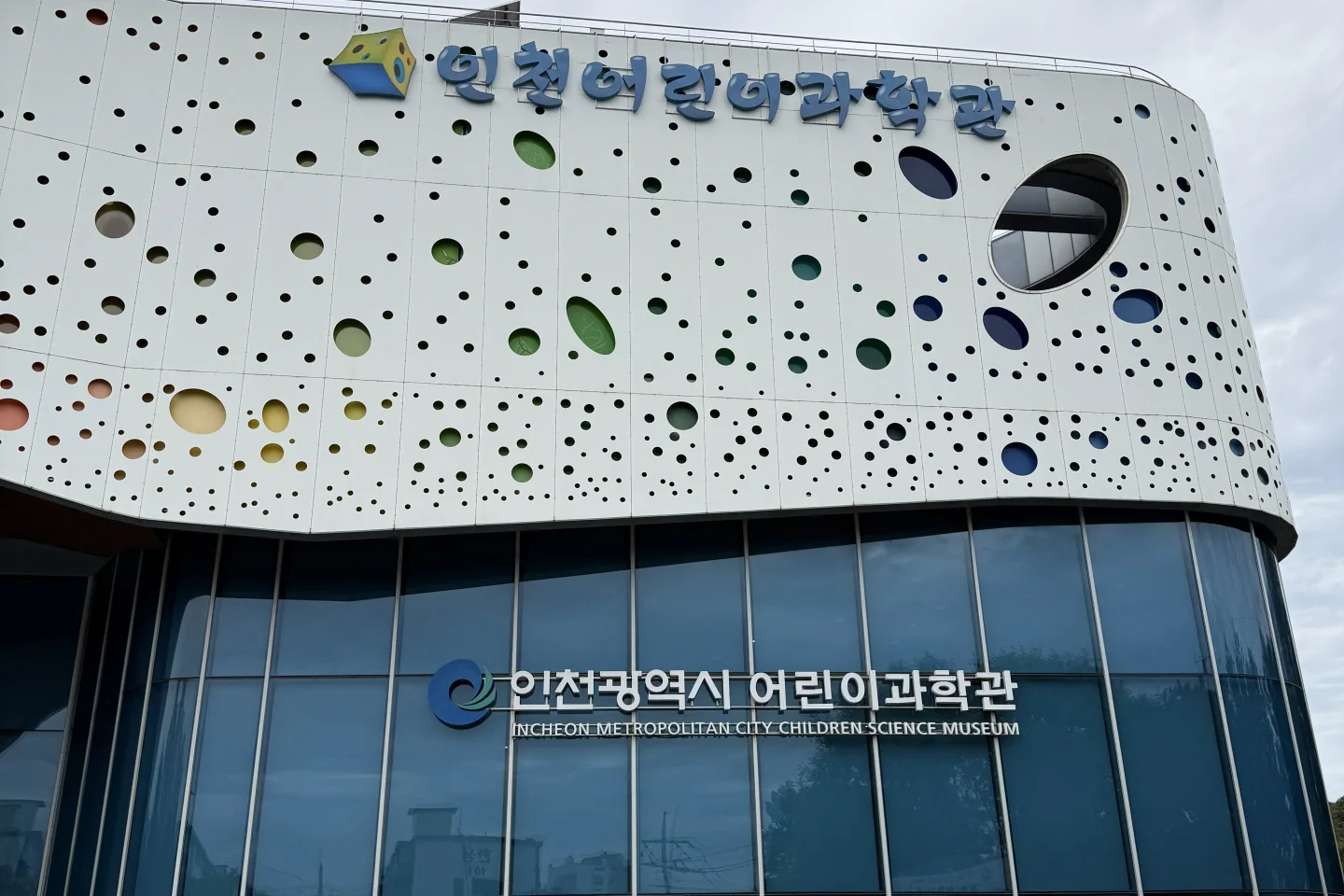 인천어린이과학관 외관, 동그란 구멍이 뚫린 흰색 건물과 파란 유리벽