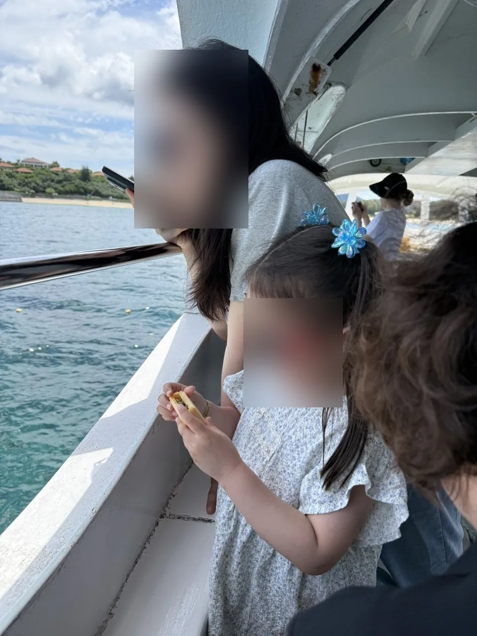 글라스보트 난간에서 물고기에게 먹이를 주는 아이와 지켜보는 엄마