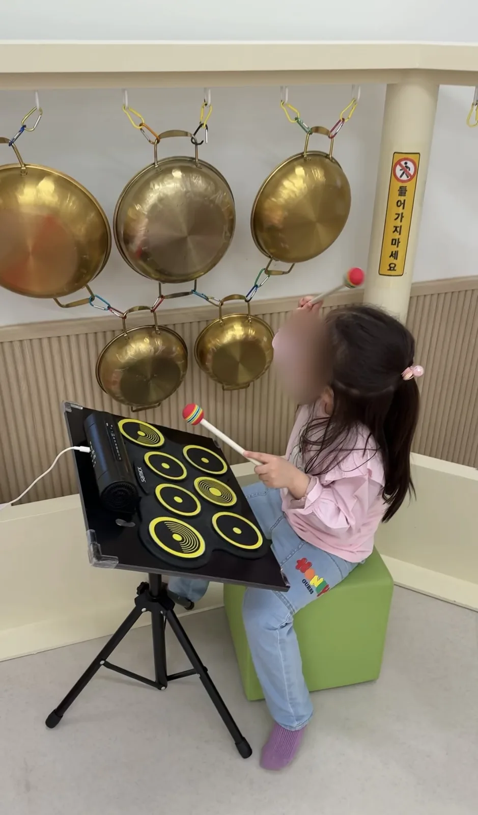 북가좌1동점 벽에 매달린 징과 드럼 패드를 치는 아이
