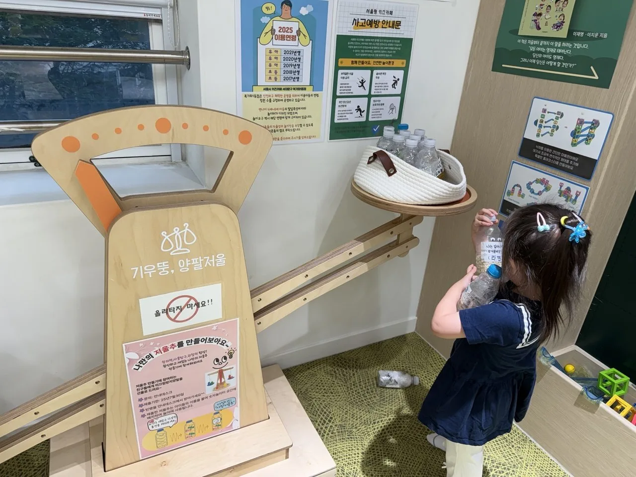 북가좌1동점 기우뚱 양팔저울 코너에서 물병 저울추를 드는 아이