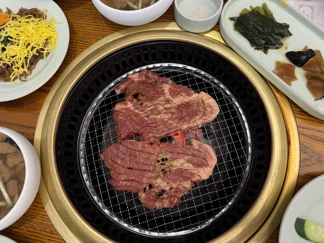 숯불 석쇠 위에 올린 양념 돼지고기와 곁들이 반찬